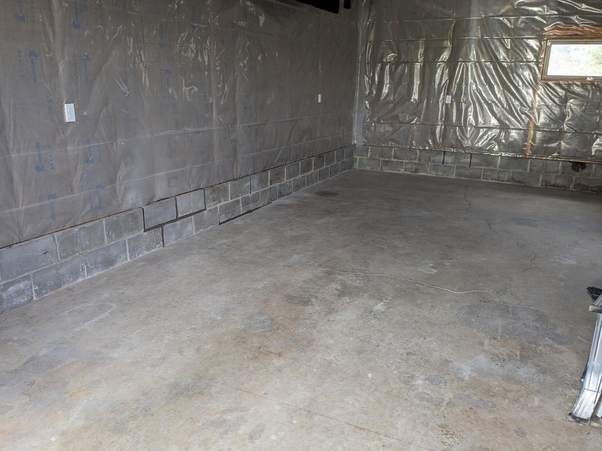 An empty basement with a concrete floor and a brick wall.