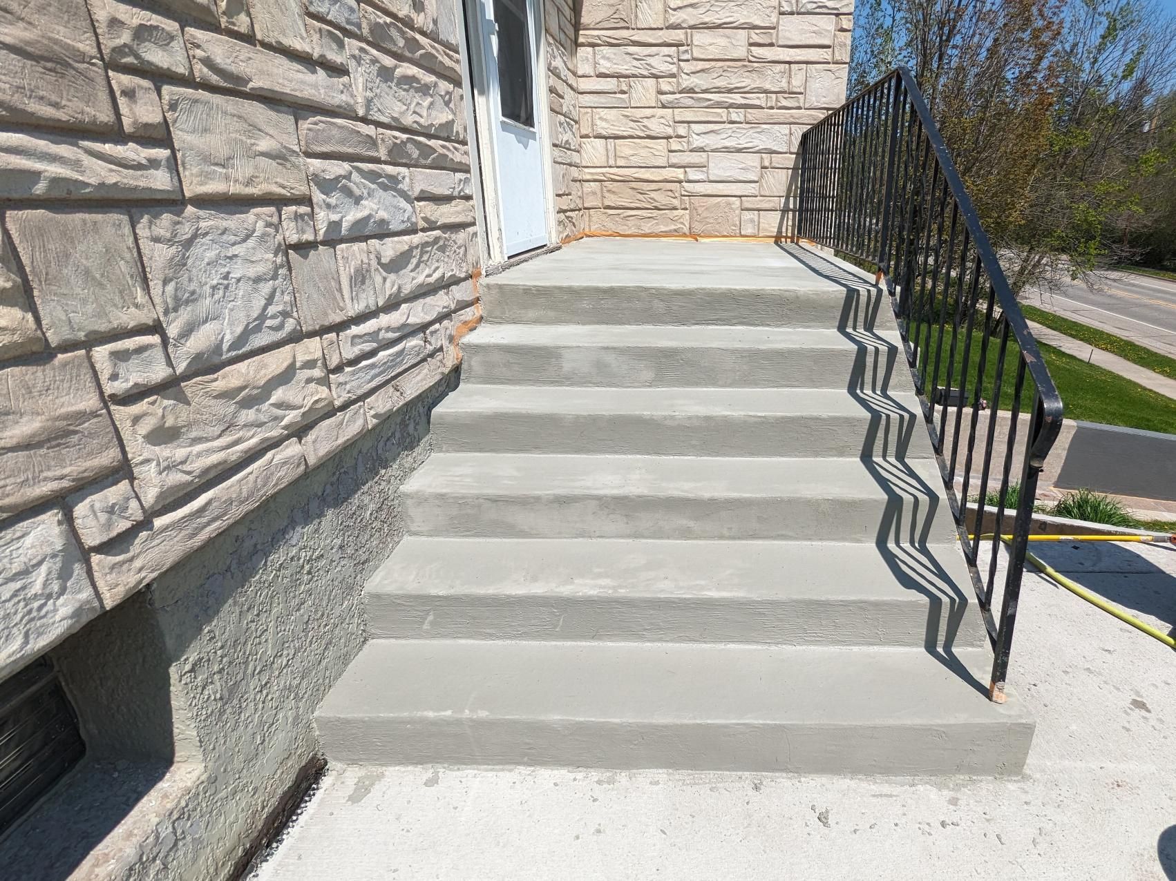 A set of concrete stairs leading up to a stone building.