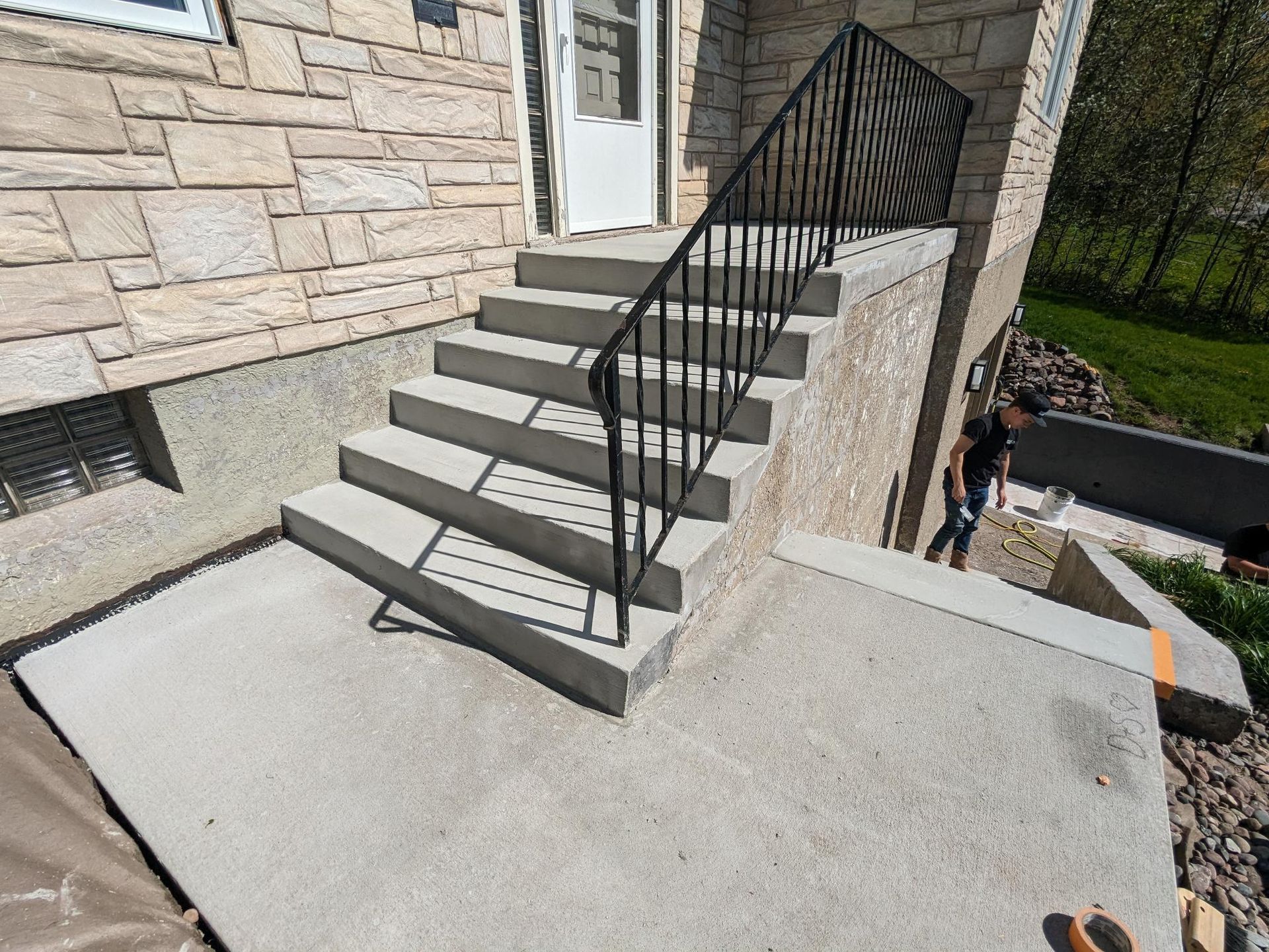 A concrete staircase with a metal railing is being built on the side of a house.
