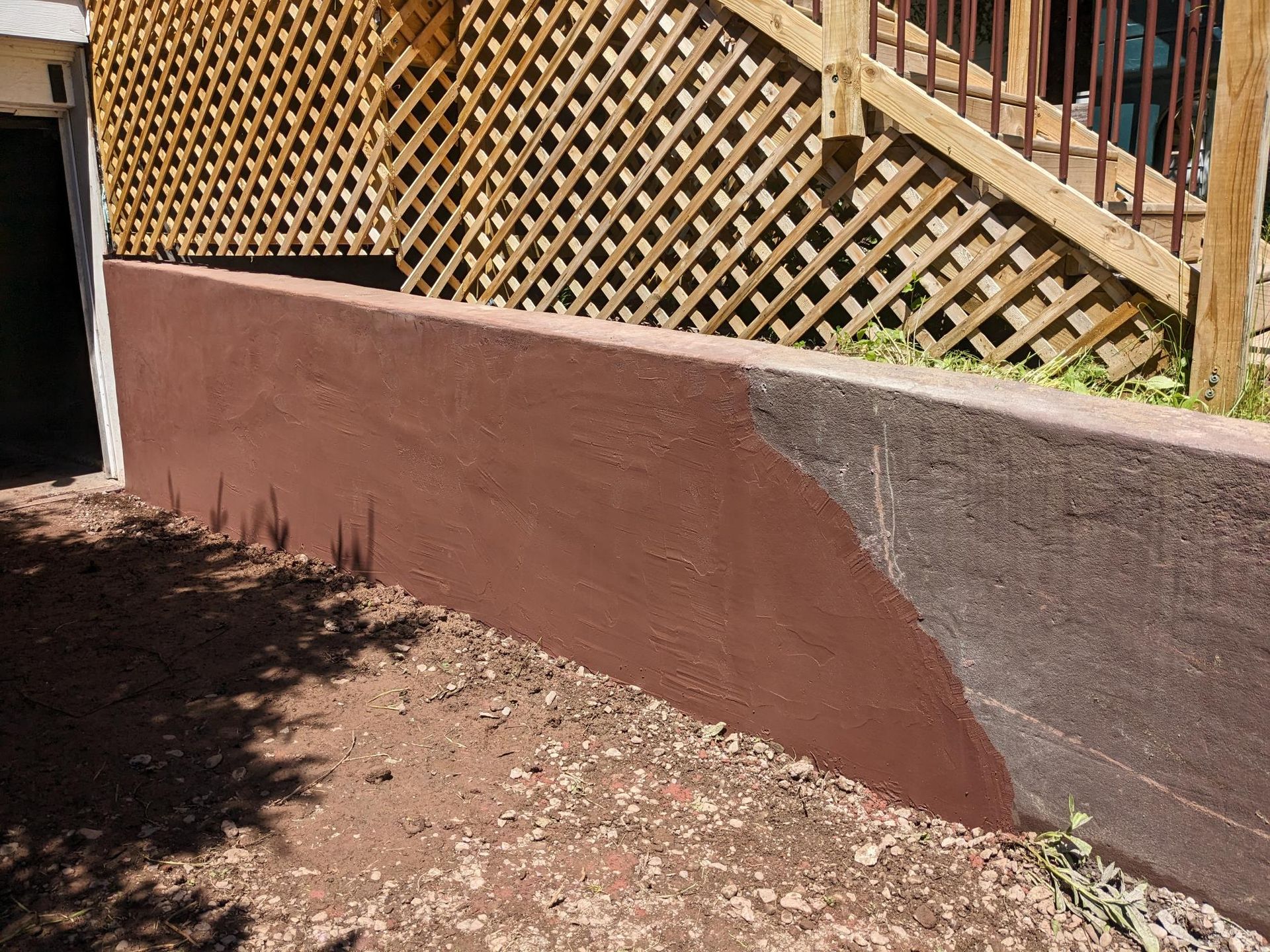 A brown wall with a wooden fence and stairs in the background.