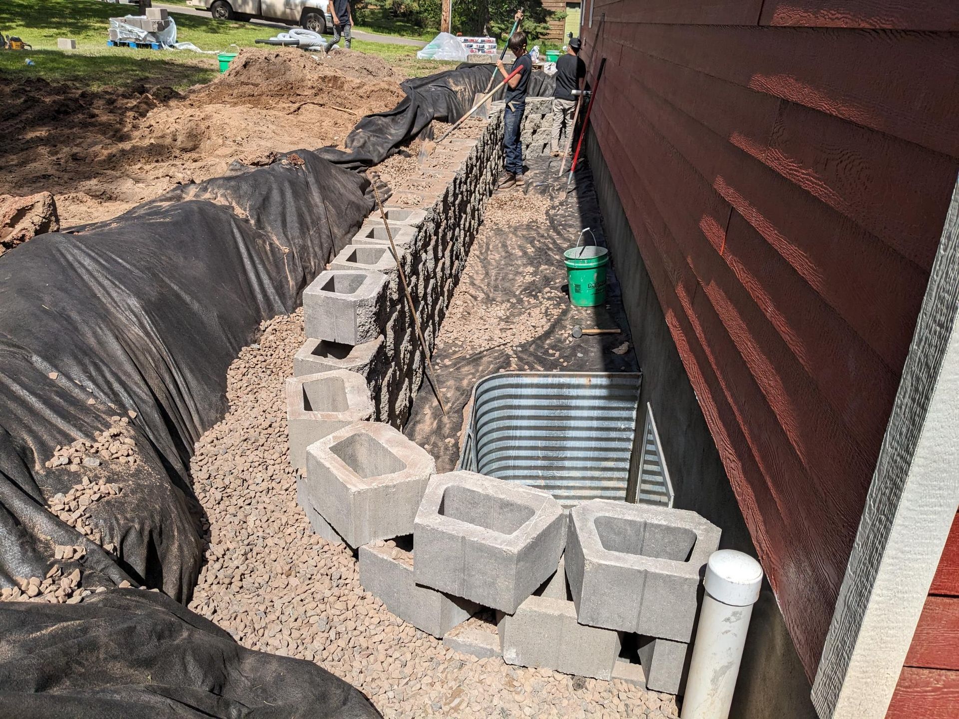 A drainage system is being built on the side of a house.