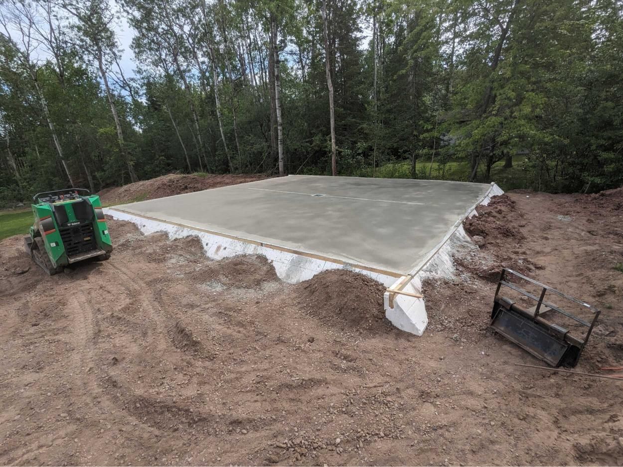A concrete foundation is being built in a dirt field.