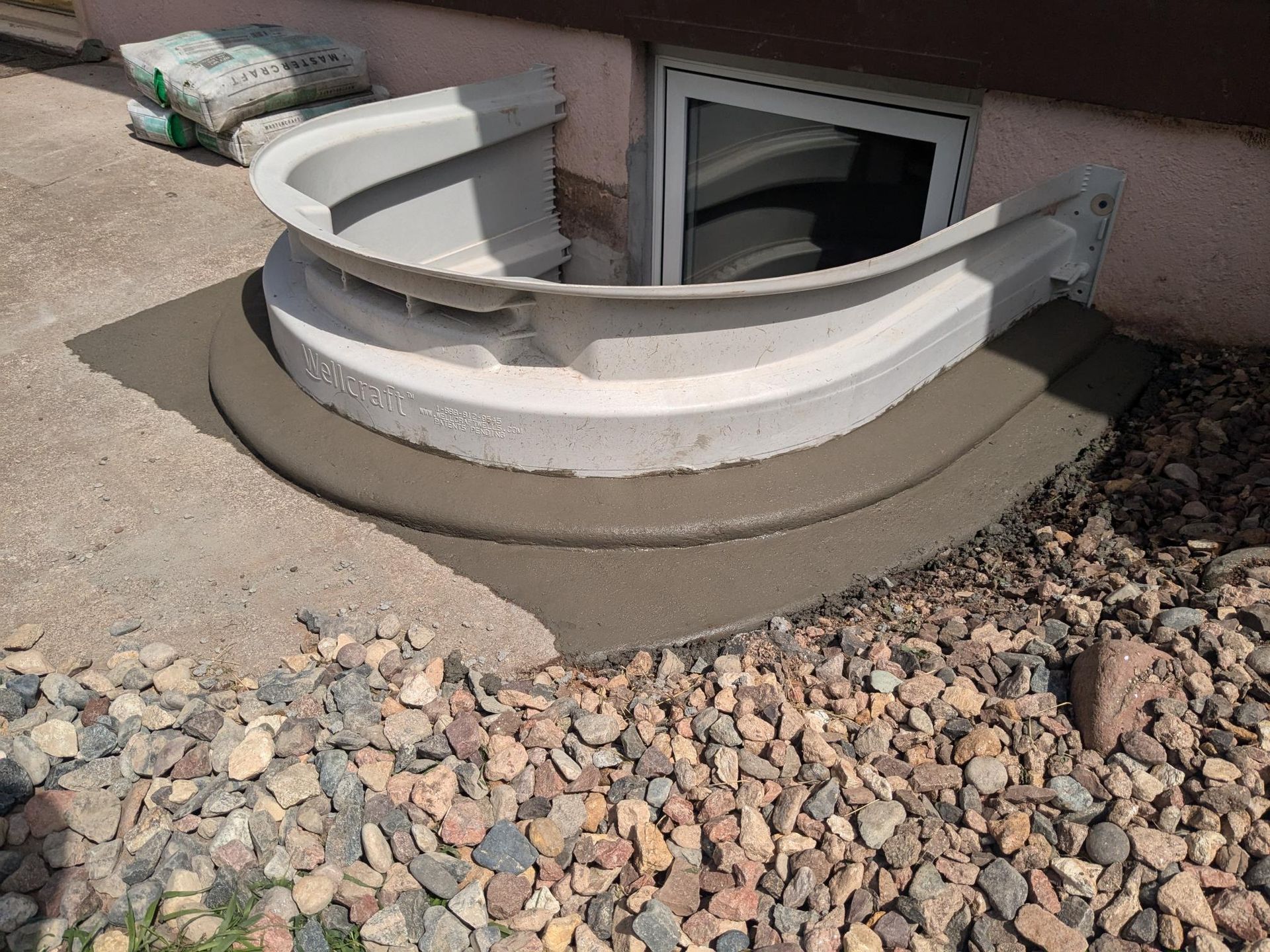 A window well is being installed on the side of a house.