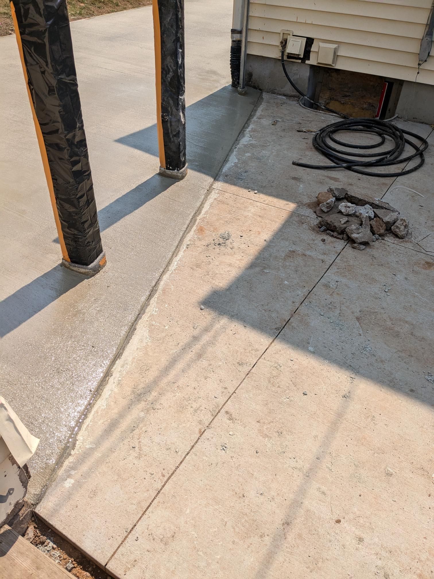 A concrete patio with a hose on it and a house in the background.