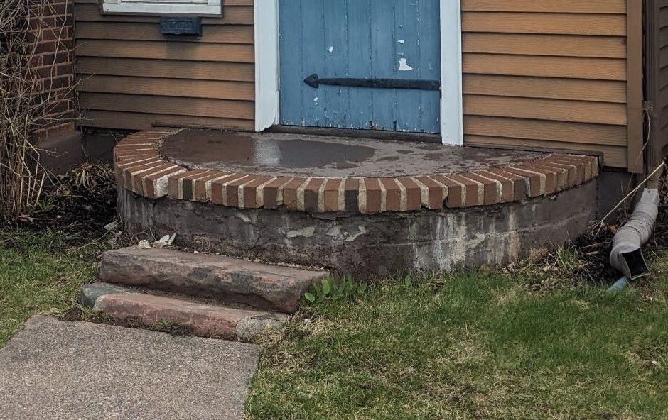 A house with a blue door and a brick porch.