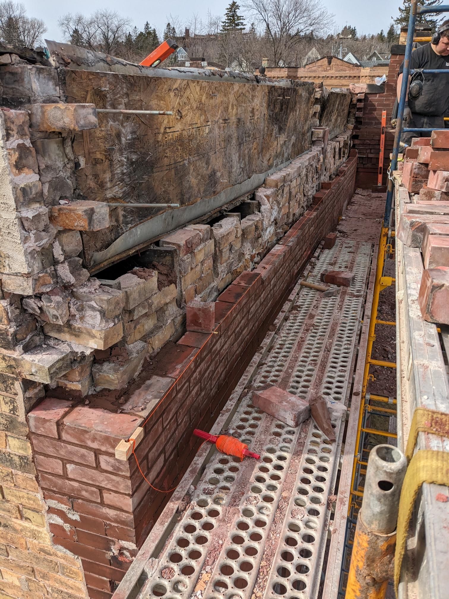 A brick wall is being built on a scaffolding.
