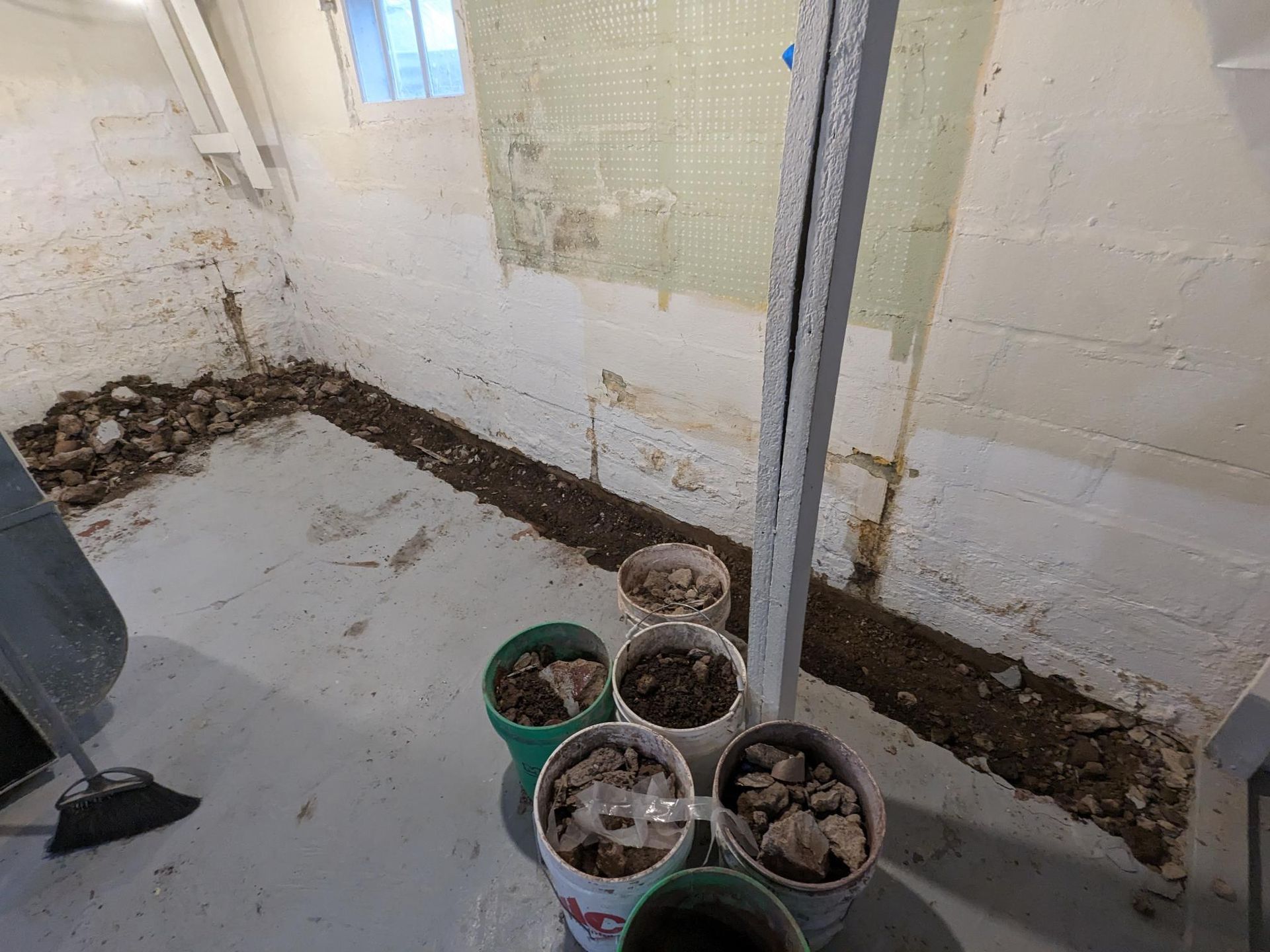 A group of buckets filled with dirt in a basement.