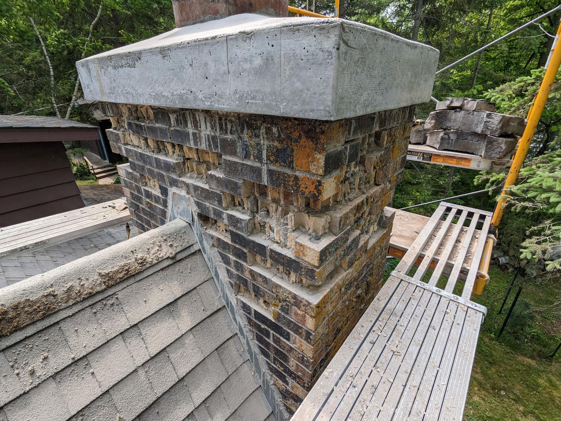 A chimney is being repaired on the roof of a house.