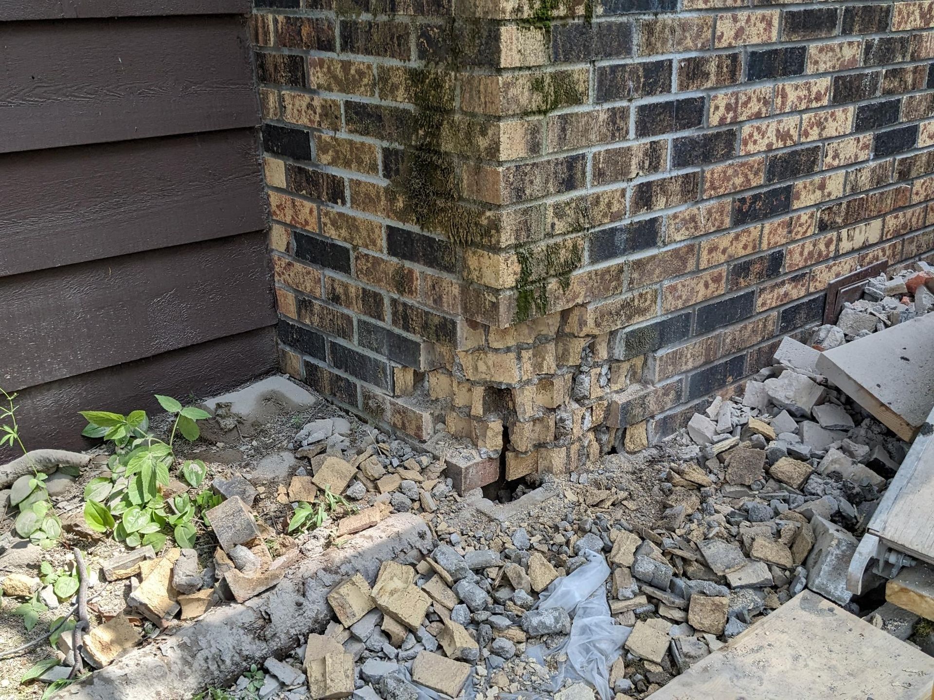 A brick wall with a hole in it and a pile of rocks in front of it