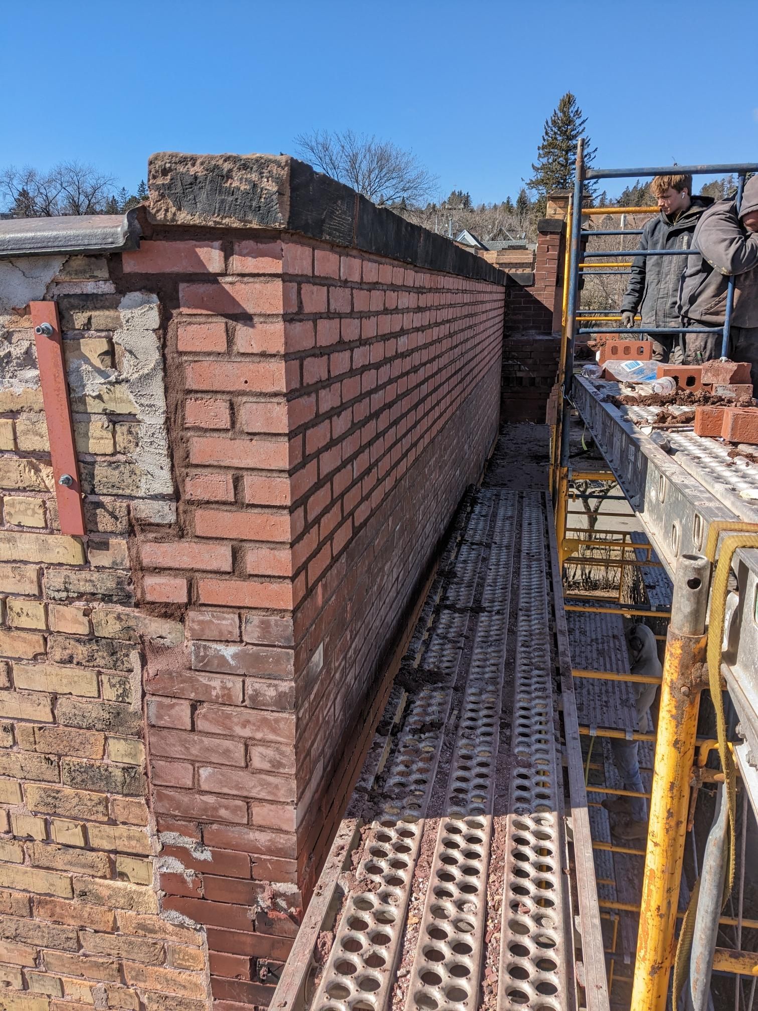 A brick wall is being built on top of a building.