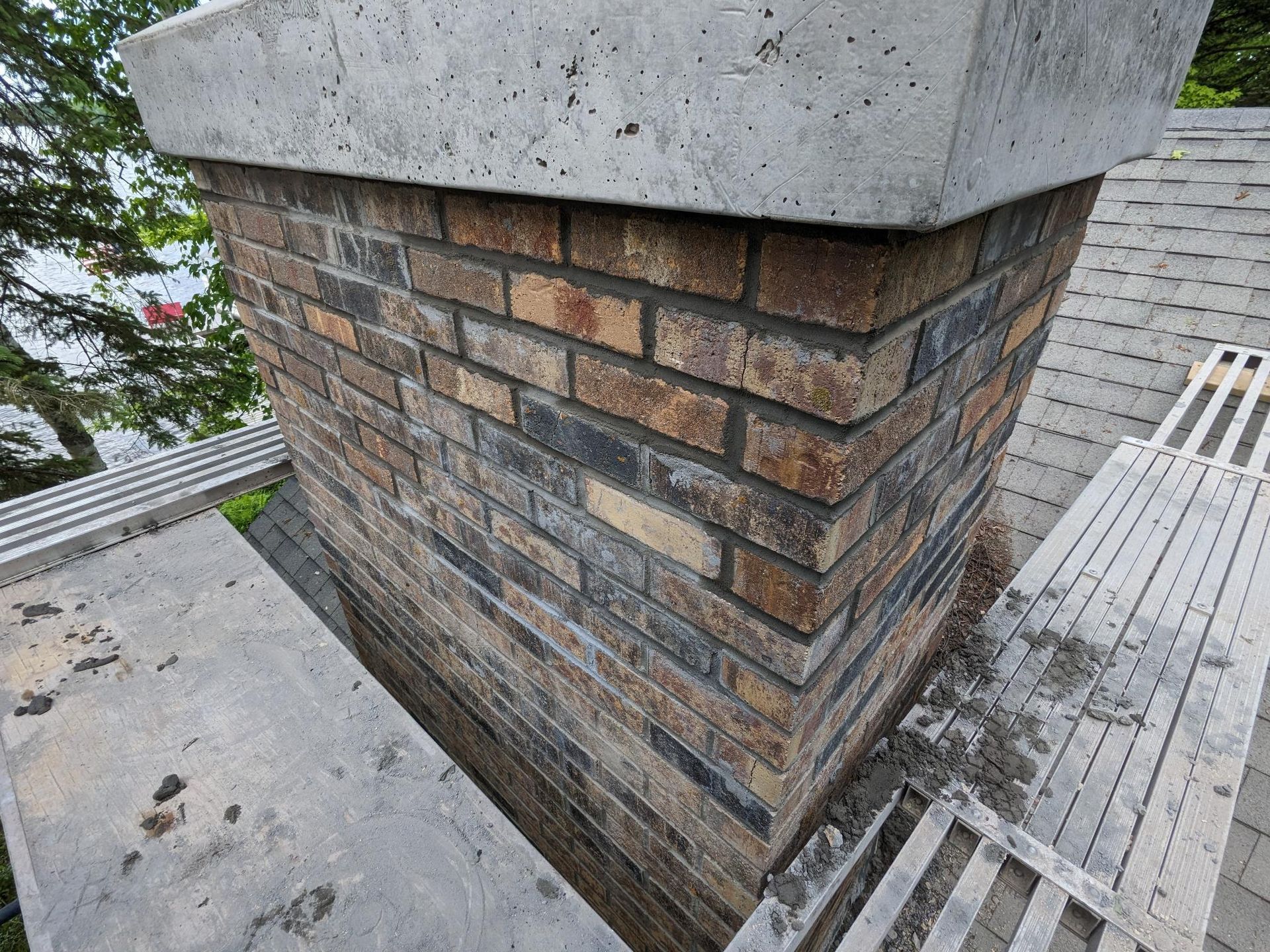 A brick chimney is being built on top of a roof.