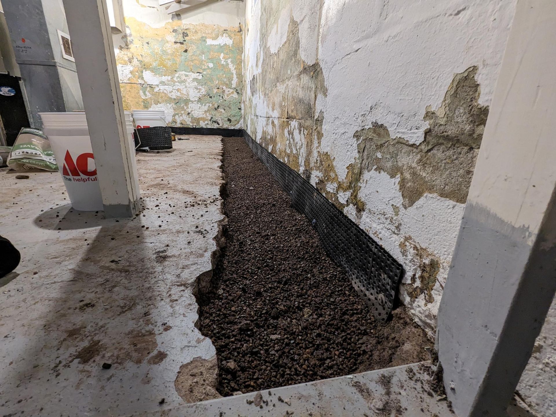 A person is standing in a basement with a hole in the wall.