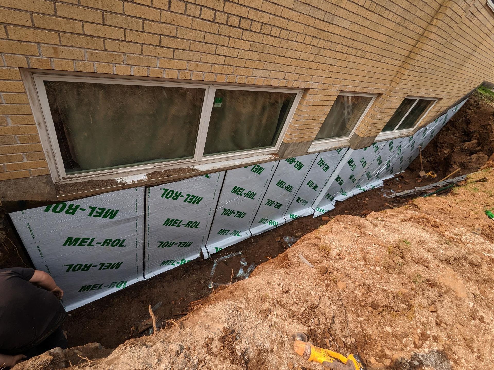 A man is working on the side of a brick building.