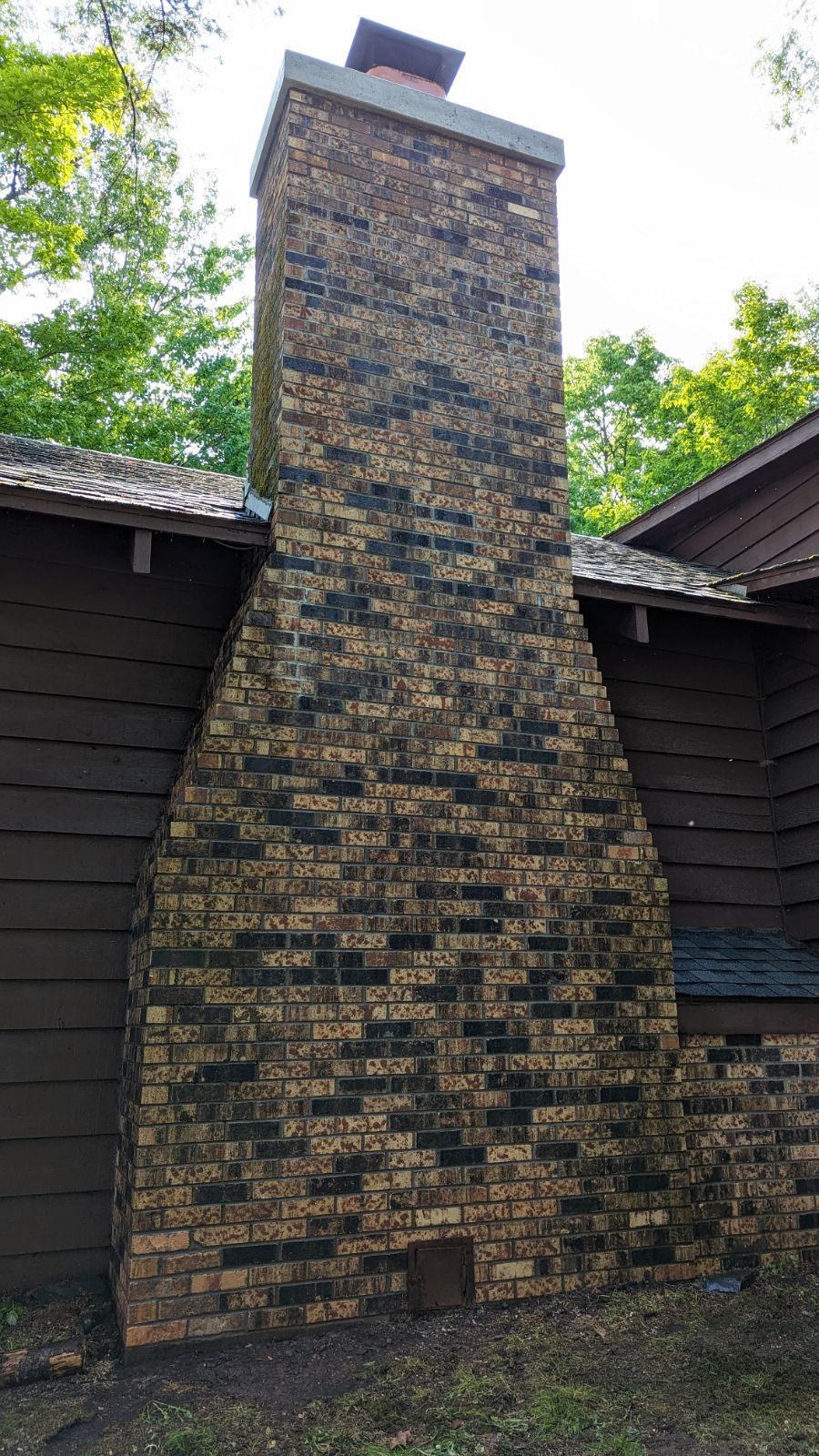 A large brick chimney is on the side of a house.