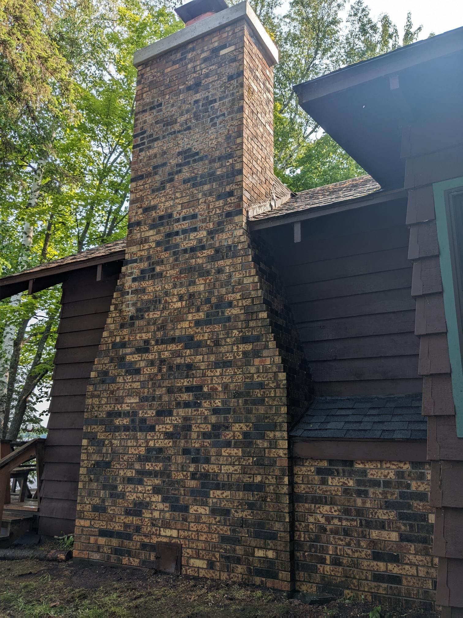 A large brick chimney is on the side of a house.