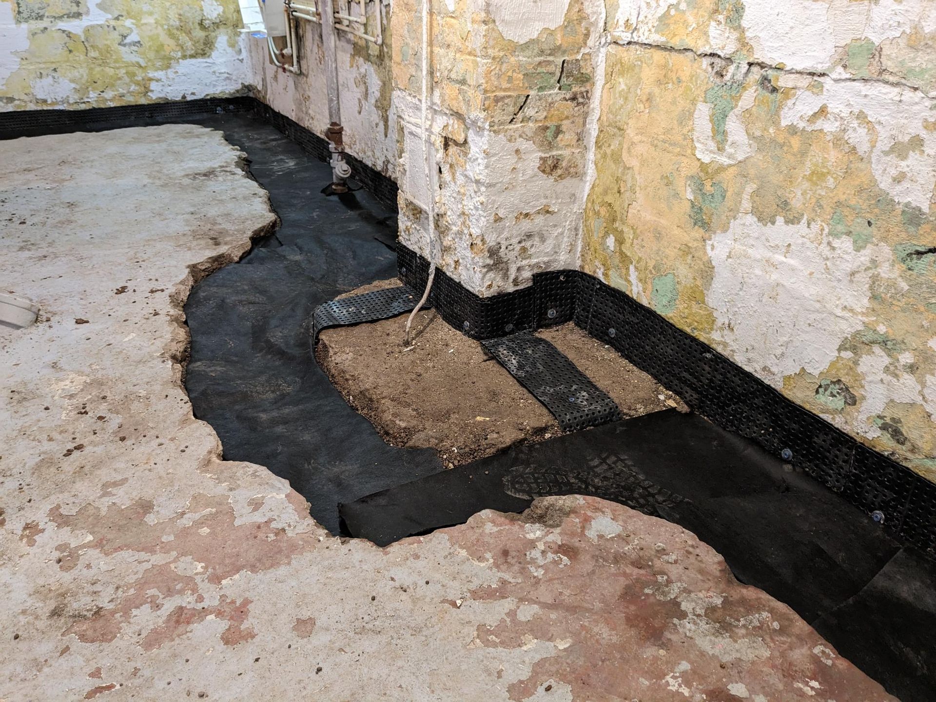 A room with a hole in the floor and a brick wall.