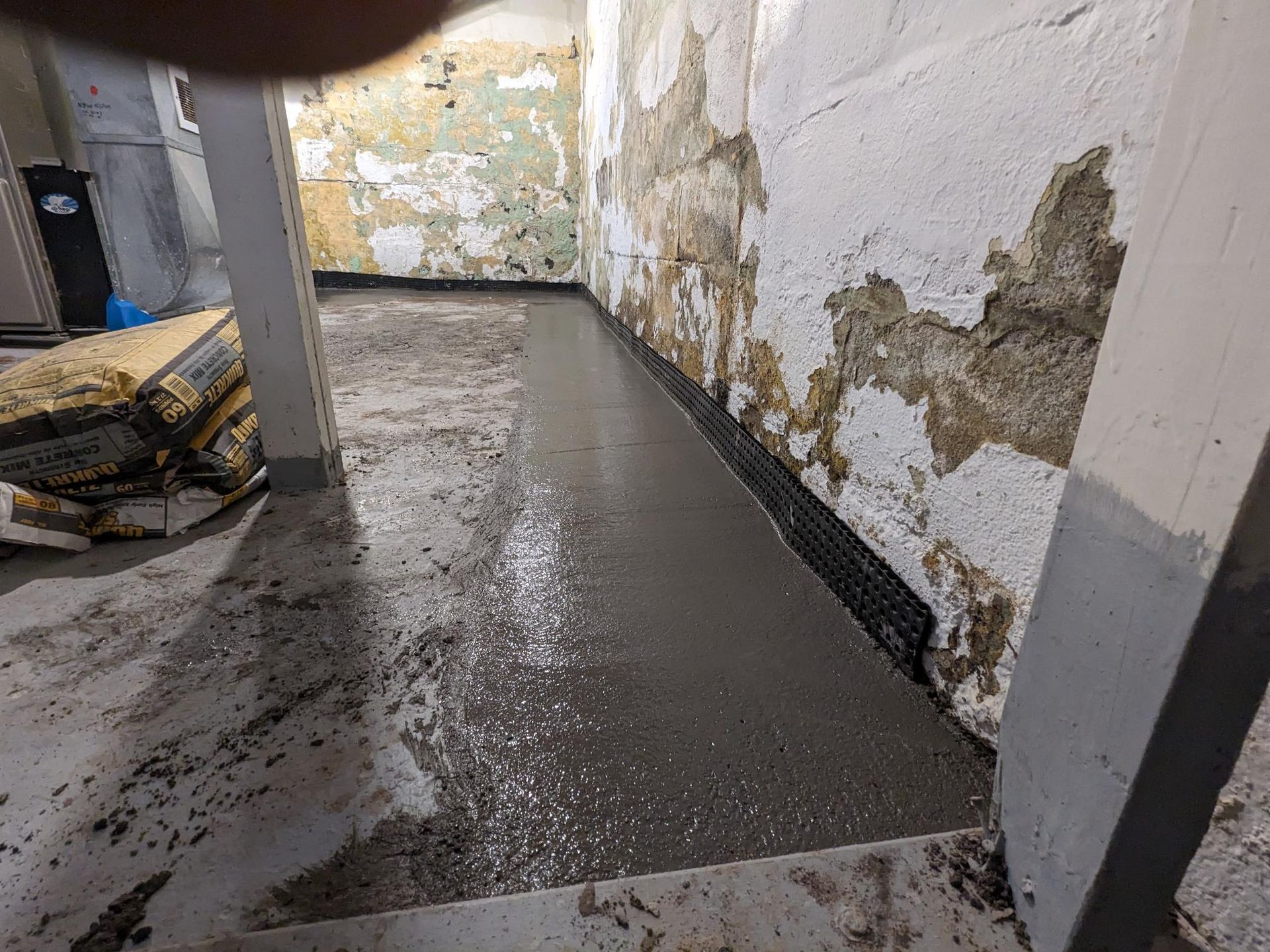 A concrete floor is being poured in a basement.