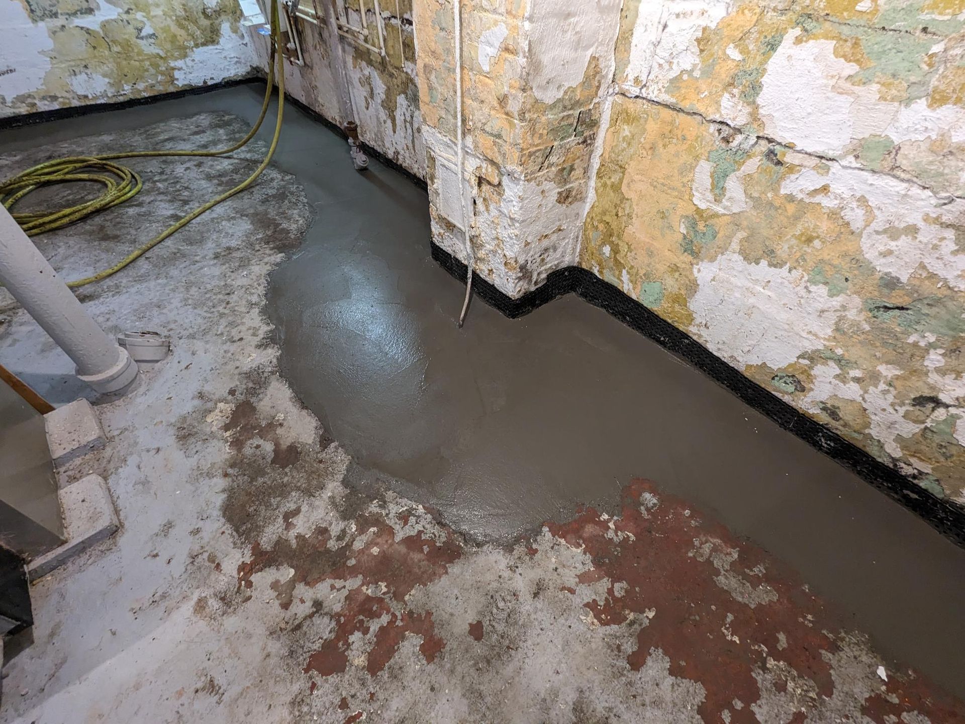 A concrete floor is being poured in a basement.