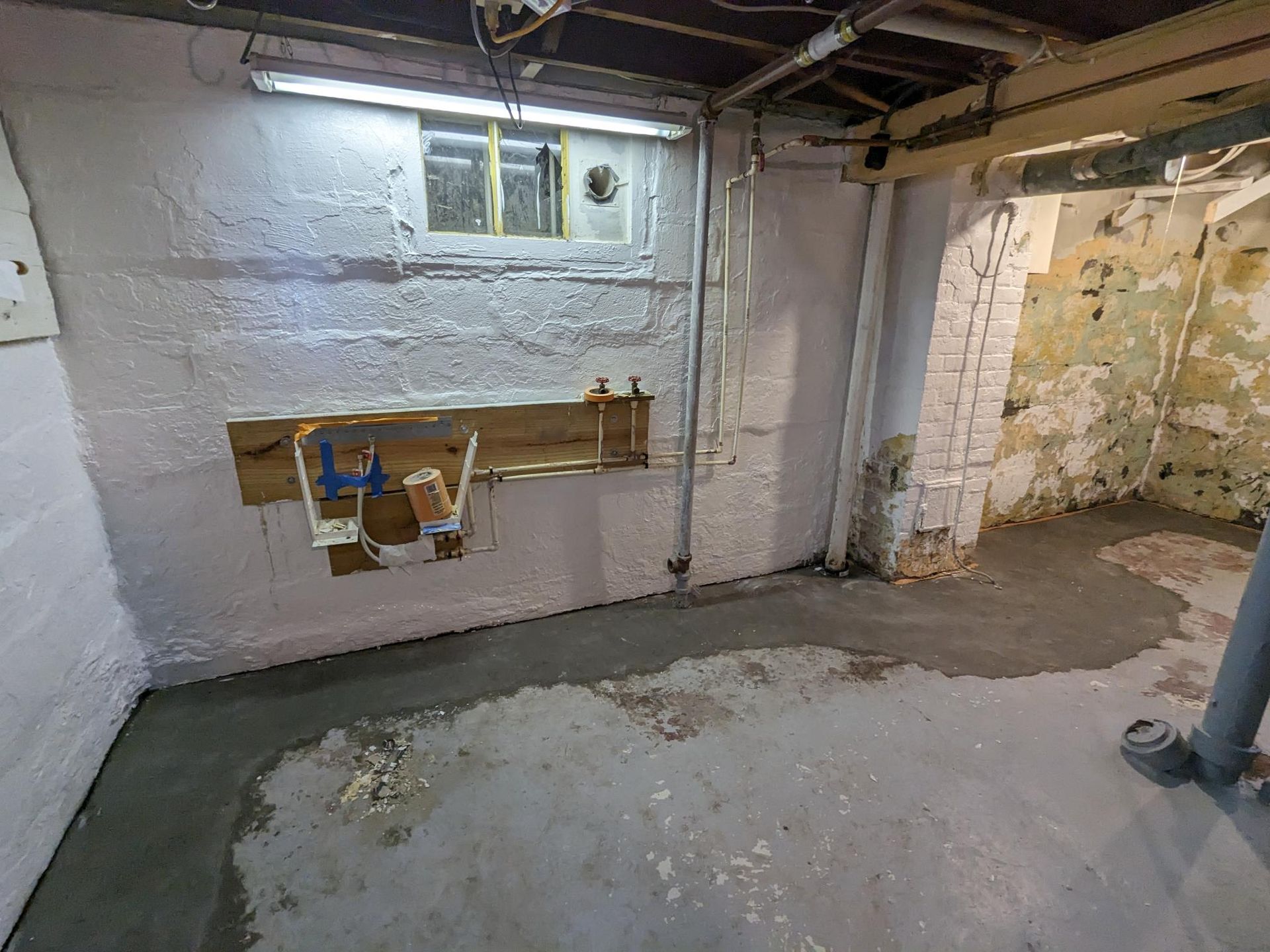 A person is standing in a basement with a hole in the wall.