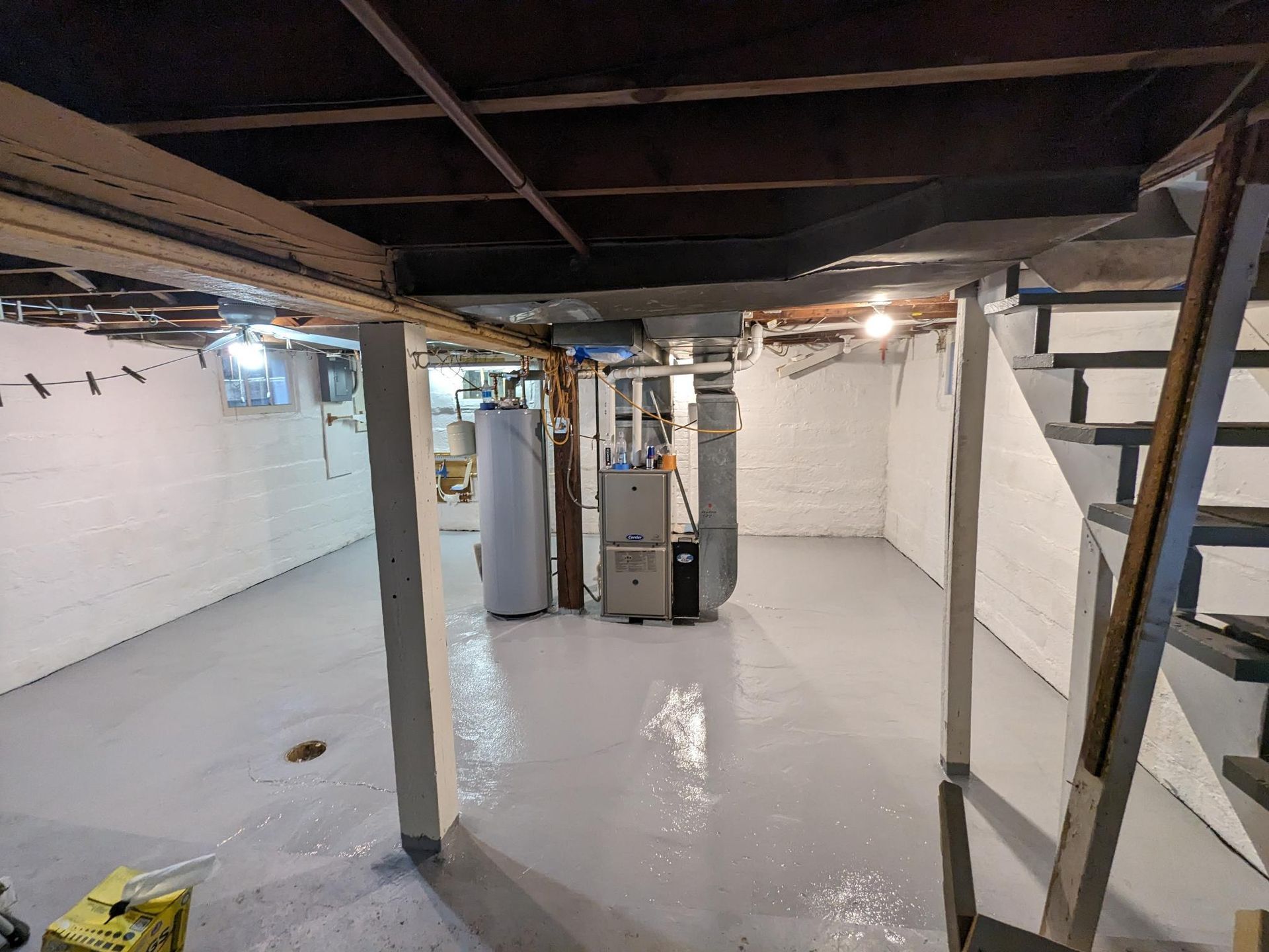 A basement with a furnace , water heater , and stairs.