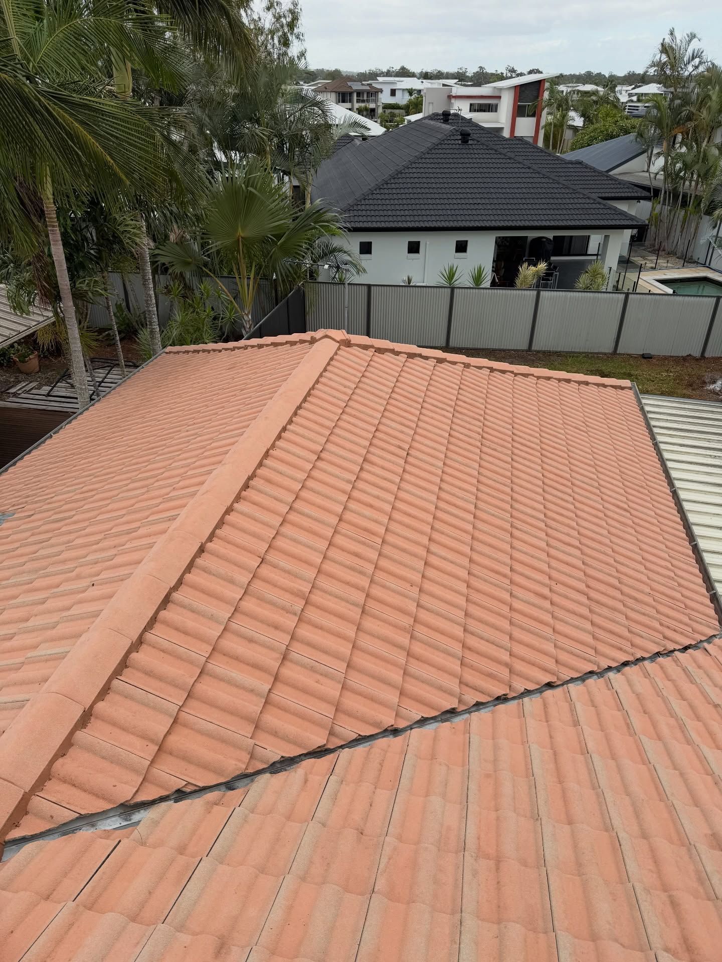 An Elevated View of a Terracotta-tiled Roof With a Prominent Ridge Cap — Coastal Pressure Solutions in Oxenford, QLD
