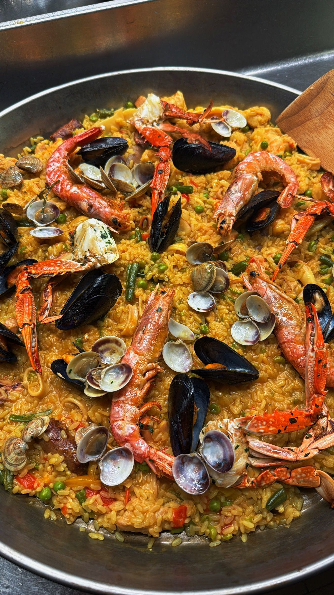 Paella con gamberi, cozze e vongole in una grande padella di metallo.