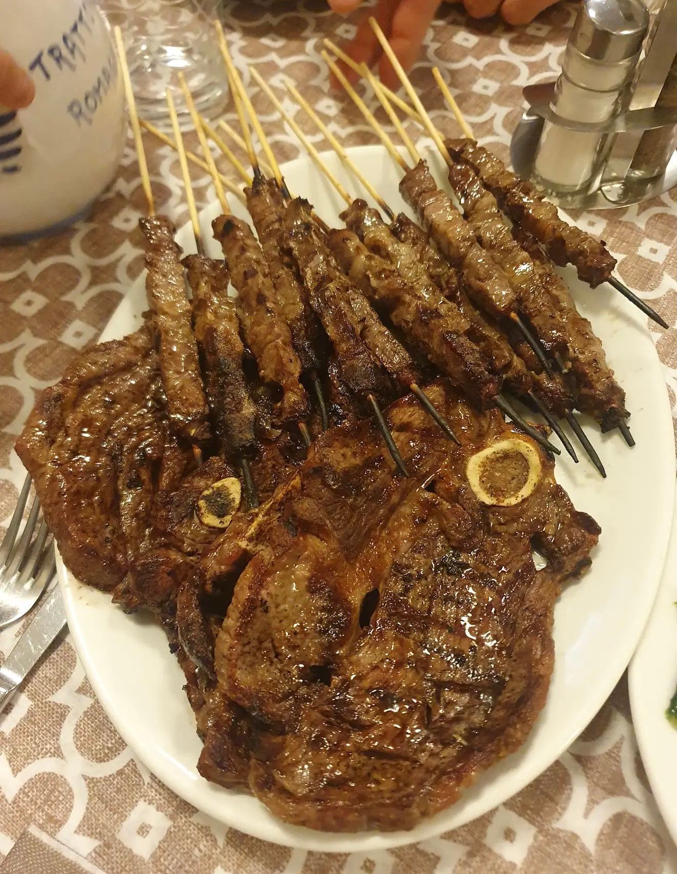 Costolette di agnello alla griglia e spiedini su un piatto bianco in un ristorante.