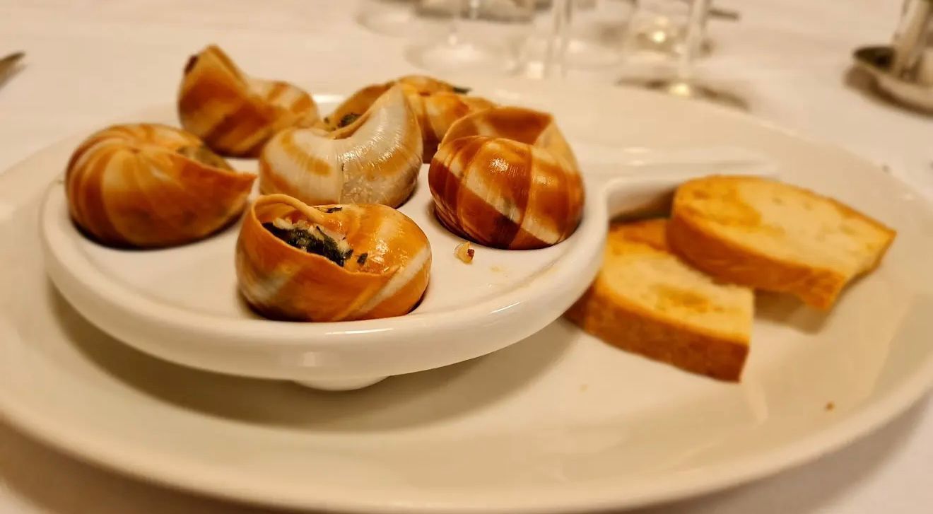 Tartufi bianchi su un piatto bianco con un'affettatrice, su una tavola di legno.