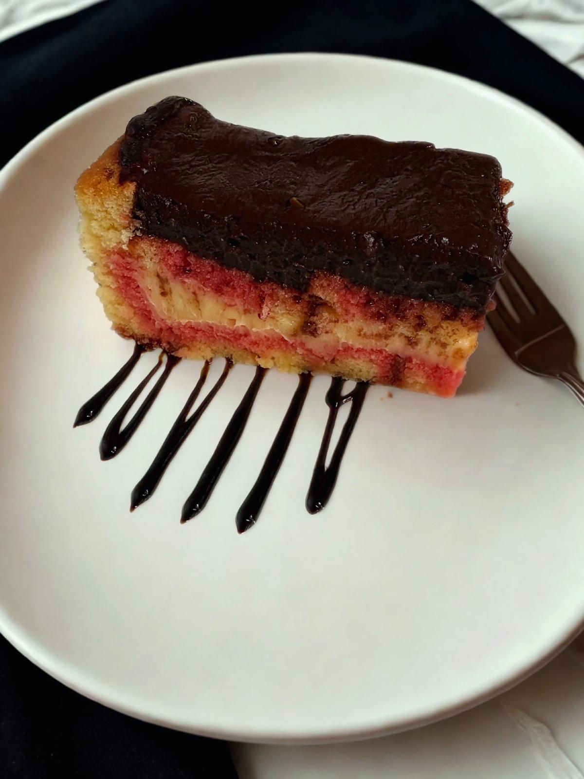 Fetta di torta di ciliegie con salsa e menta su un piatto bianco.