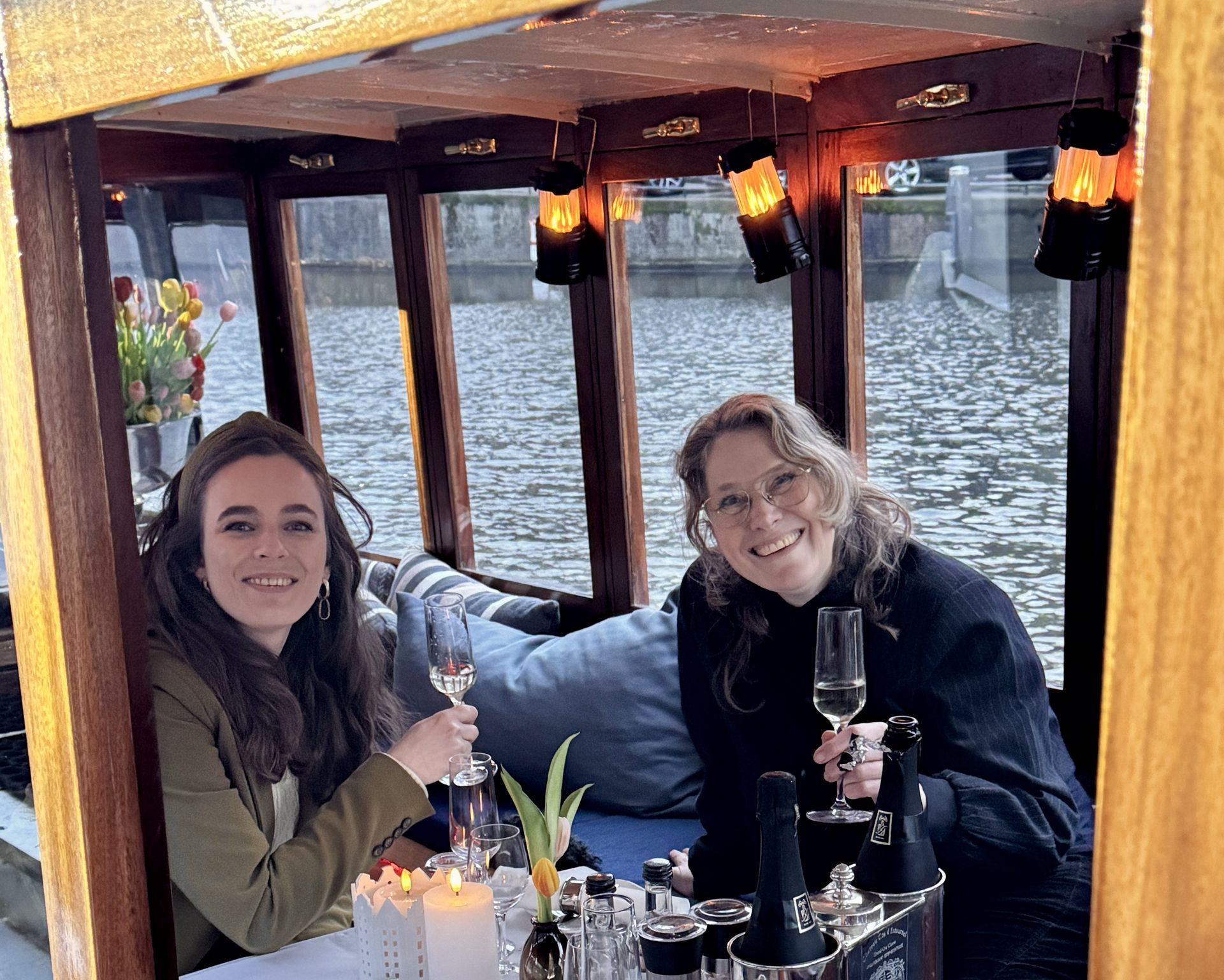 Boat interior with wine, flowers, and seating arranged around a barrel table on a blue surface.