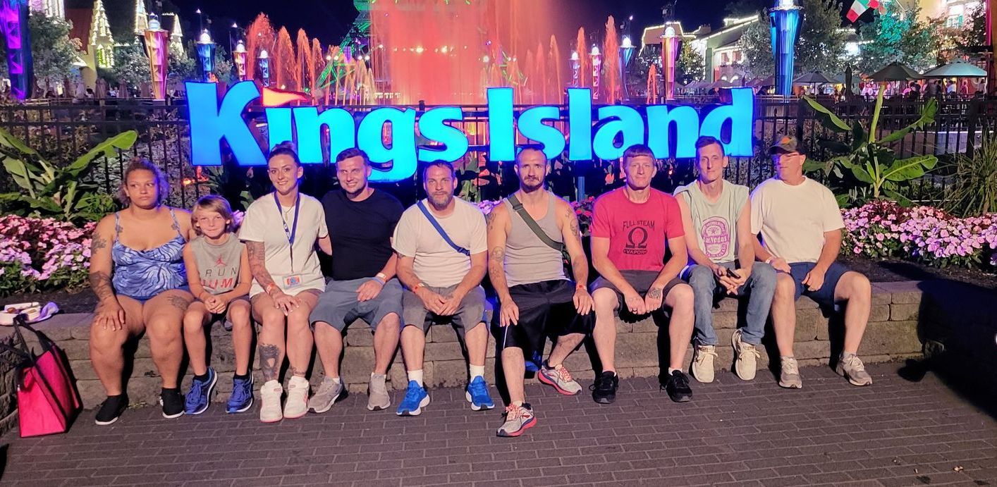 A group of people are posing for a picture in front of a sign that says kings island.