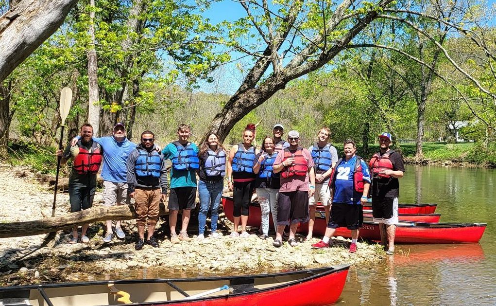 A group of people are posing for a picture next to a river.
