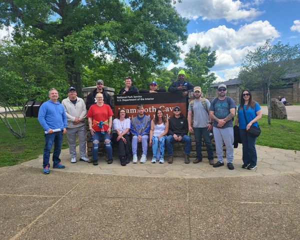 A group of people are posing for a picture in front of a sign.