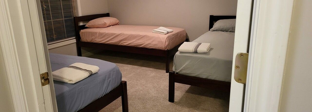 A bedroom with two beds and a sliding glass door.