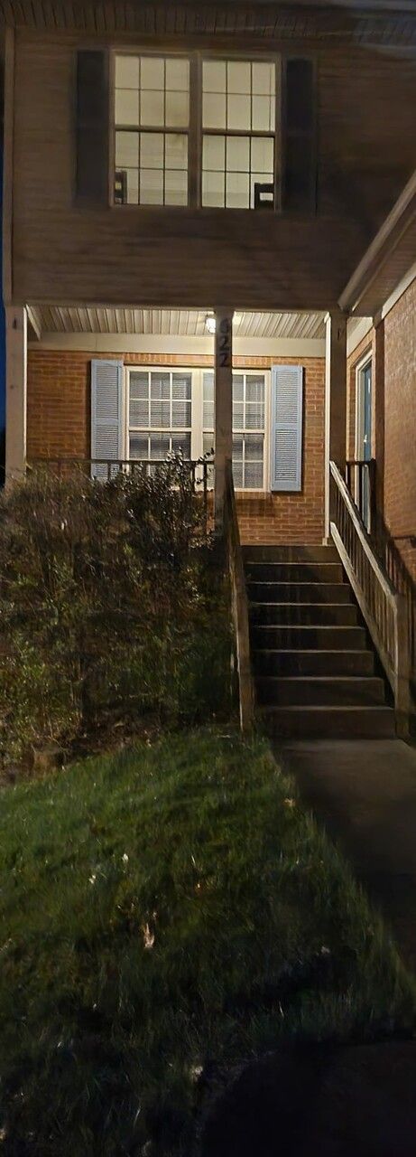 The front of a brick house with stairs leading up to it at night.