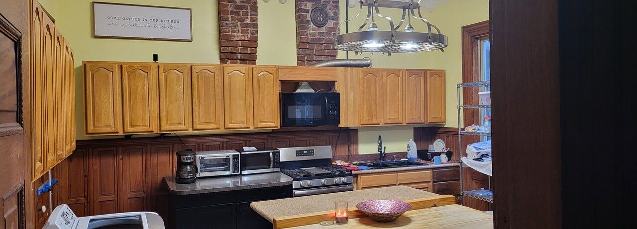 A kitchen with wooden cabinets , a stove , a microwave and a sink.