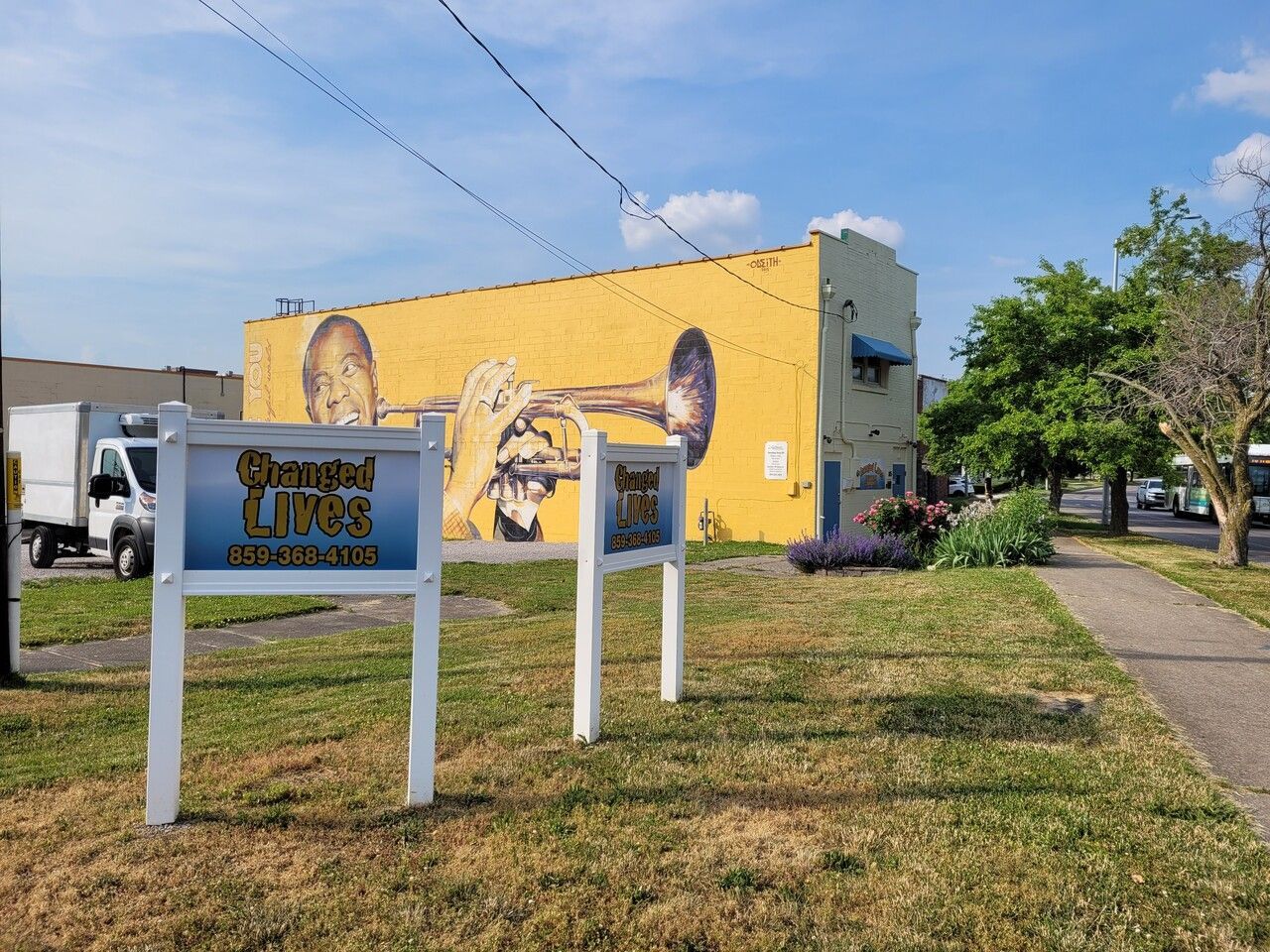 A yellow building with a mural of a man playing a trumpet on the side of it.