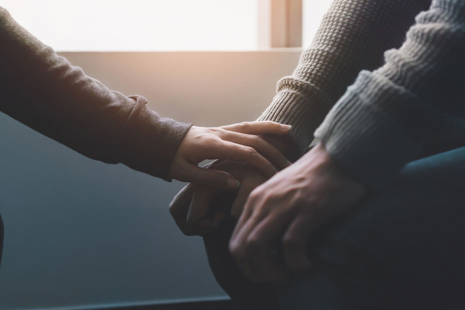 A man and a woman are holding hands while sitting in a chair.