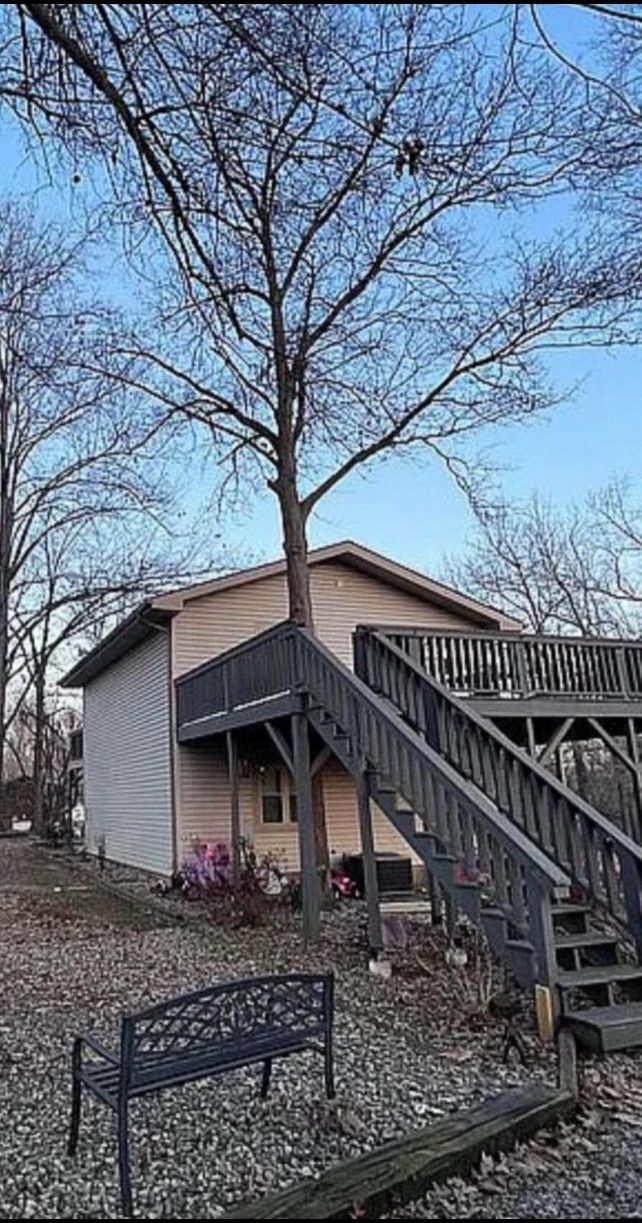 A house with stairs leading up to it and a bench in front of it.