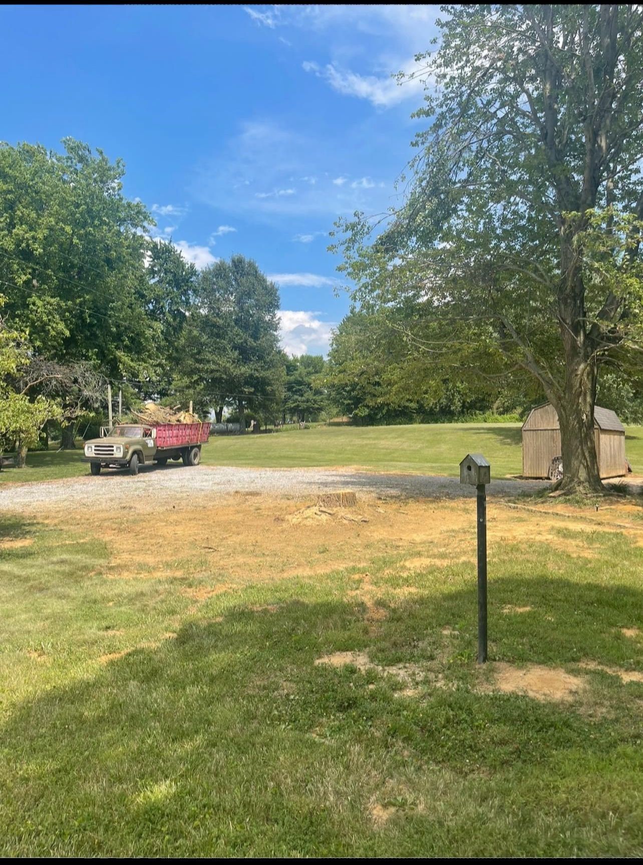 A red dump truck is parked in the middle of a grassy field.