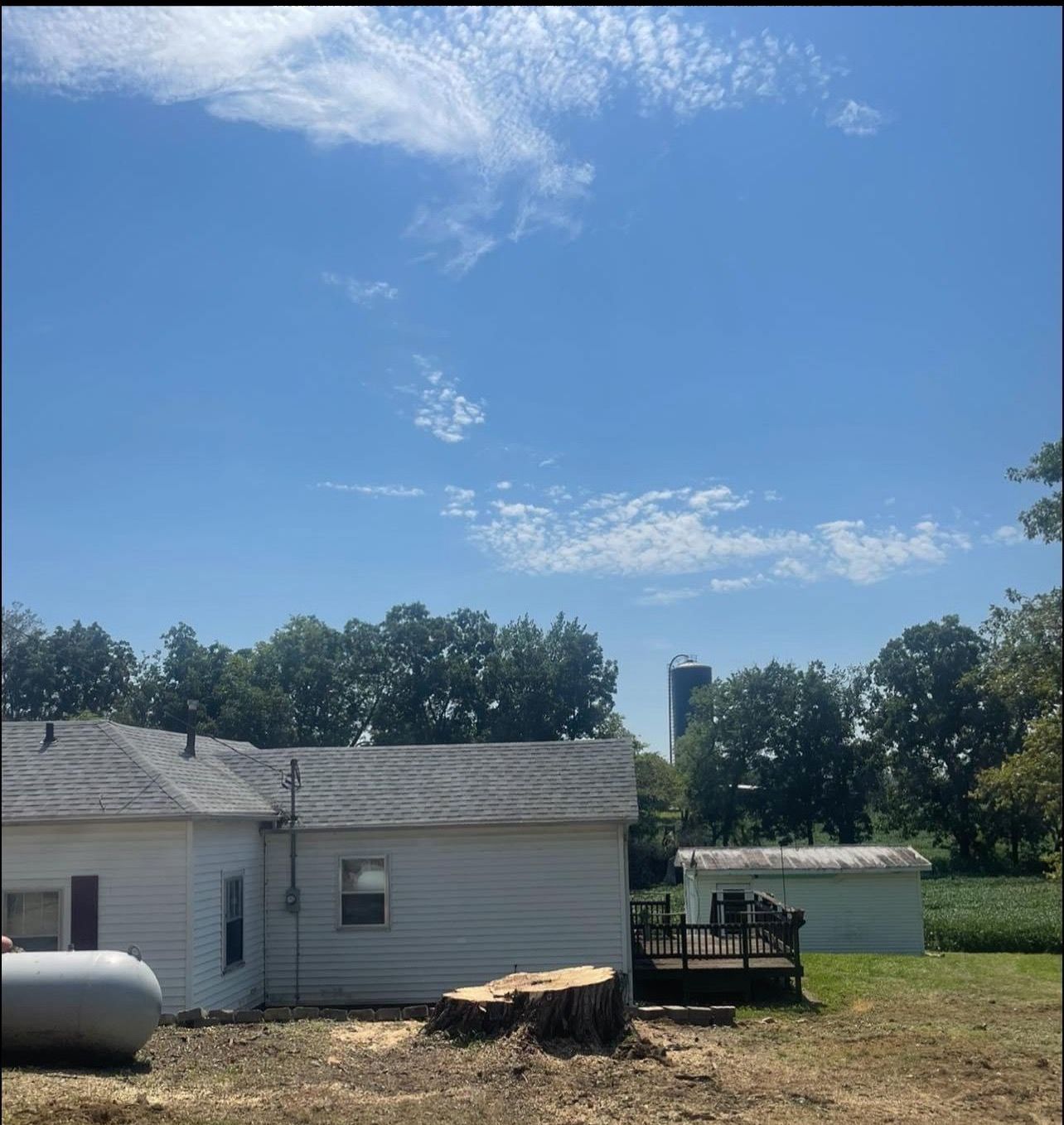 A white house with a propane tank in front of it