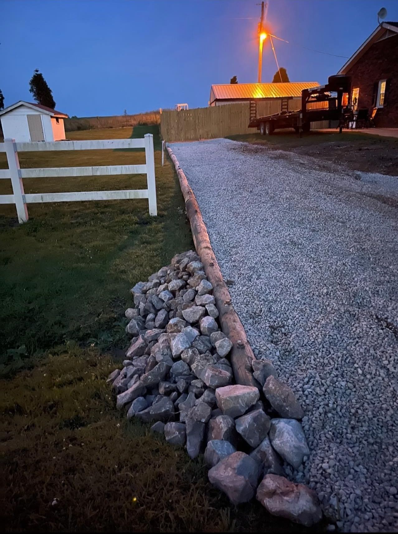 A gravel driveway with a white fence in the background