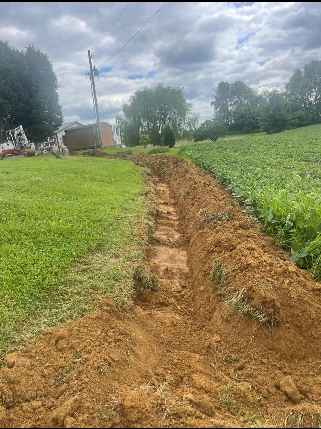A trench is being dug in the middle of a grassy field.
