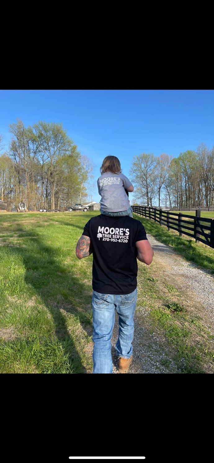 A man is carrying a child on his shoulders down a dirt road.