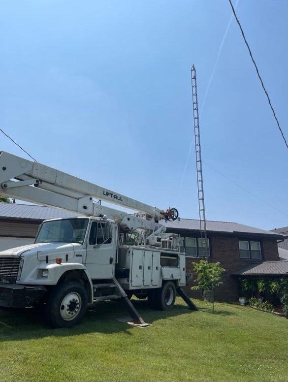 A white truck with a ladder attached to it is parked in front of a house.