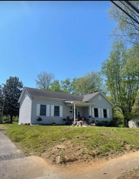 A small white house with a porch and a blue sky in the background.