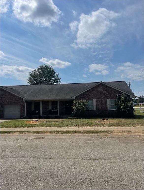 A brick house with a garage and a porch on a sunny day.