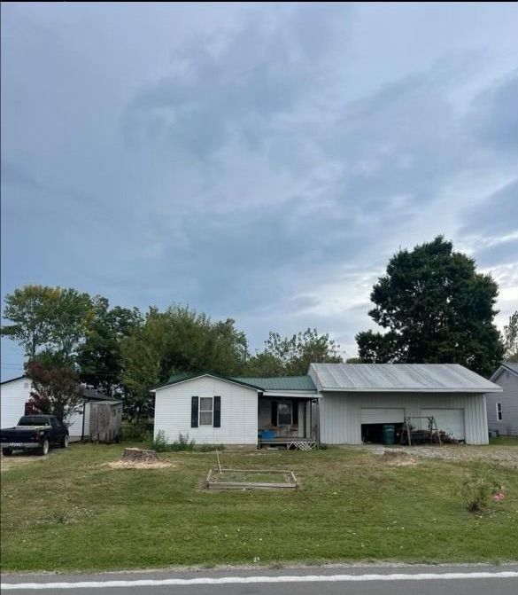 A white house with a green roof is sitting in the middle of a lush green field.