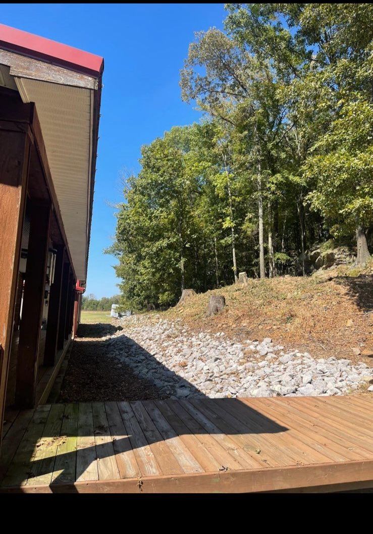 A wooden walkway leading to a house with trees in the background.