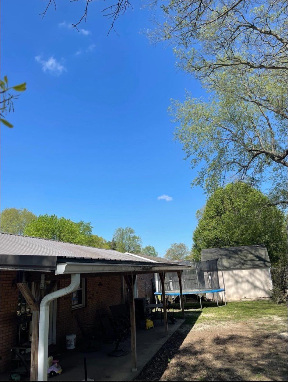 A house with a porch and a trampoline in the backyard on a sunny day.